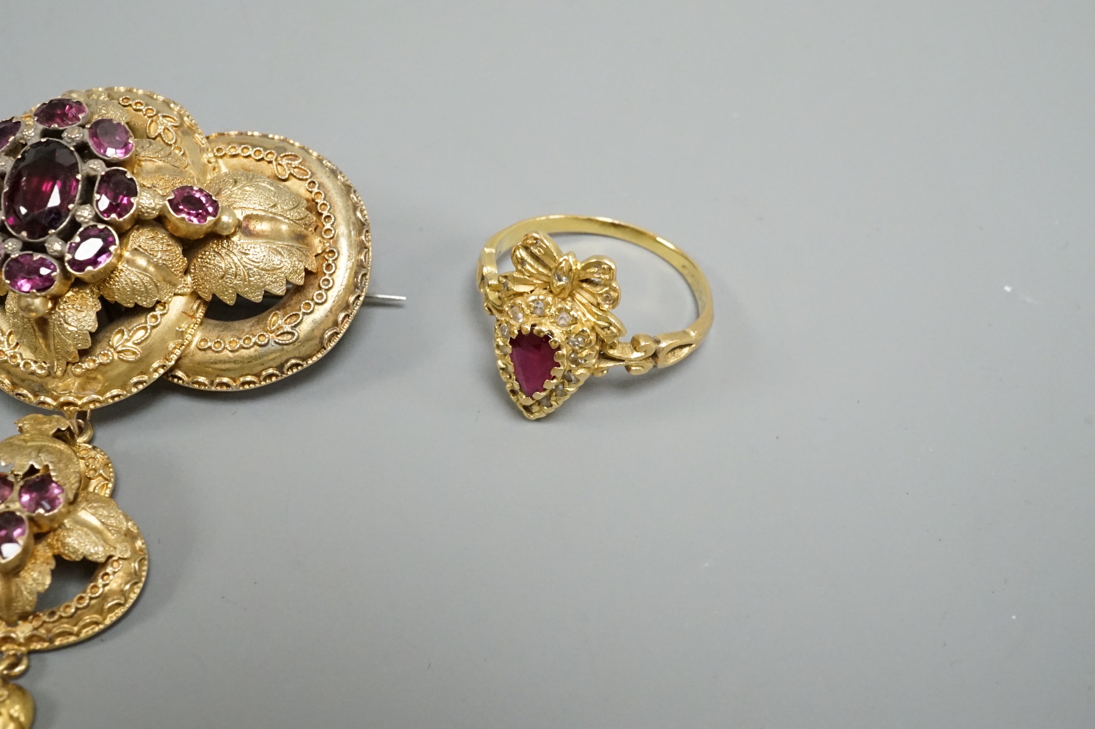 A Victorian yellow metal and garnet cluster set drop brooch, 50mm, a modern 18ct gold, ruby and diamond heart shaped ring with ribbon bow crest and a micro mosaic set cross pendant, on a 9k chain.